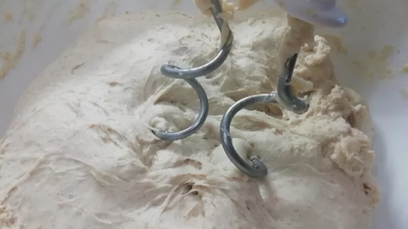 2. Do misky pridáme polohrubú múku, roztopené maslo, zbytok vlažného mlieka, kvások, žĺtok, prášok do pečiva, kryštálový cukor, soľ. Vymiesime vláčne cesto rukou, môžeme si pomôcť kuchynským robotom.