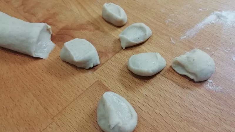 4. Vykysnuté cesto preložíme na pomúčenú dosku, ešte raz premiesime kvôli kvasinkám. Bochníček narežeme na časti, z ktorých si urobíme dlhšie šúľky, ktoré krájame na menšie kúsky cca 1,5 cm, pečením narastú.