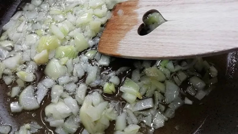 2. Na kvalitnejšiu panvicu pridáme olej a maslo, rozohrejeme. Pridáme cibuľu, ktorú orestujeme do sklovita. Zasypeme cukrom, premiešame a pridáme kapustu.