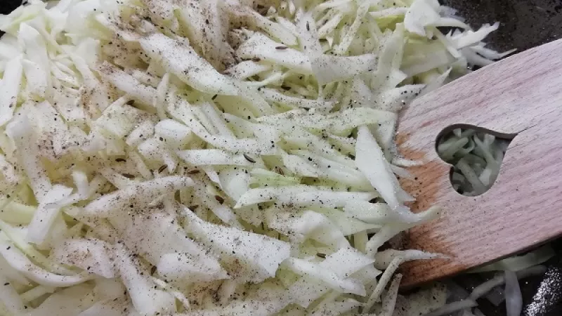 3. K smaženiu hlávkovej kapusty pridáme aj soľ, mleté čierne korenie, drvenú alebo celú rascu. Premiešame. Takto ochutenú kapustu budeme na panvici restovať.
