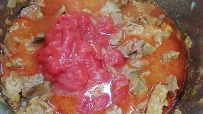 4. Mäso sledujeme, aby sa nerozvarilo. Dĺžka dusenia záleží od druhu a kvality mäsa. K polomäkkému mäsu pridáme aj roztlačený cesnak podľa chuti a ošúpané, na menšie kúsky nakrájané paradajky (polené paradajky, paradajkové pyré), ktoré guláš zahustia.