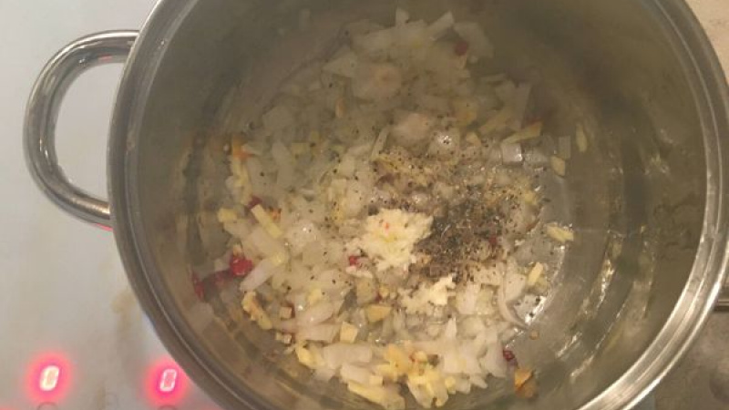 3. V hrnci necháme opražiť nakrájanú cibuľu, pretlačený cesnak, zázvor a chilli papričku nakrájané na drobné kúsky. Po chvíli pridáme tekvicu so zemiakom a chvíľku restujeme.