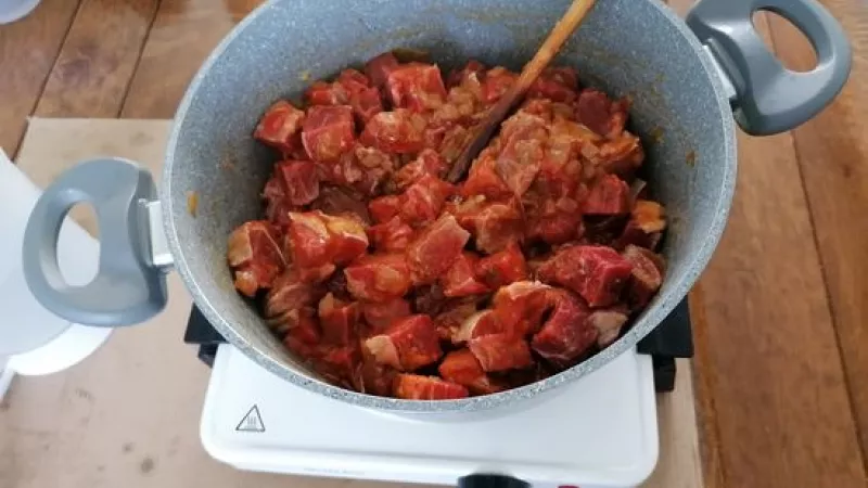 2. Keď je cibuľa do sklovita, nie až do zlatista, pridáme červenú mletú papriku a hneď aj na kocky nakrájané mäso. Sprudka ho opekáme. 