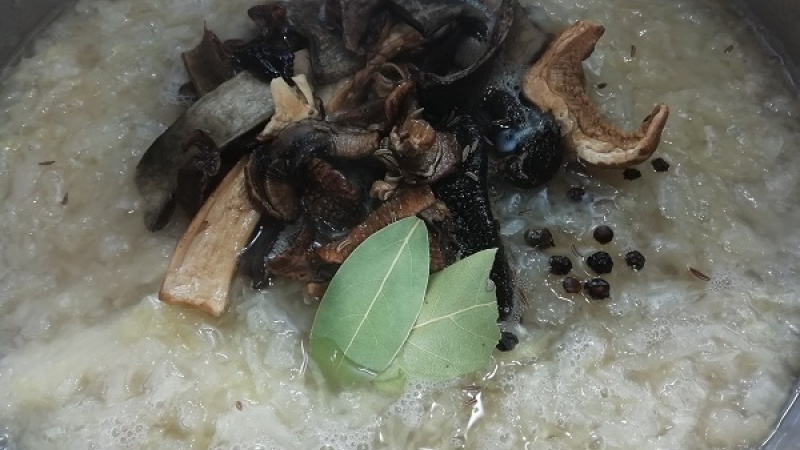 2. Kyslú kapustu vložíme do väčšieho hrnca, pridáme klobásu, údené rebierko, od vody vytlačené huby a korenie podľa chuti.