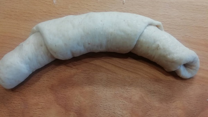 6. Rožky pripravíme tak, že si bochníček vyvaľkáme do trojuholníka. Potom trojuholník zrolujeme, jemne vyformujeme do tvaru rožka. Plech na pečenie vystelieme papierom na pečenie. Na takto pripravený plech ukladáme jednotlivé tvary, nie blízko seba.