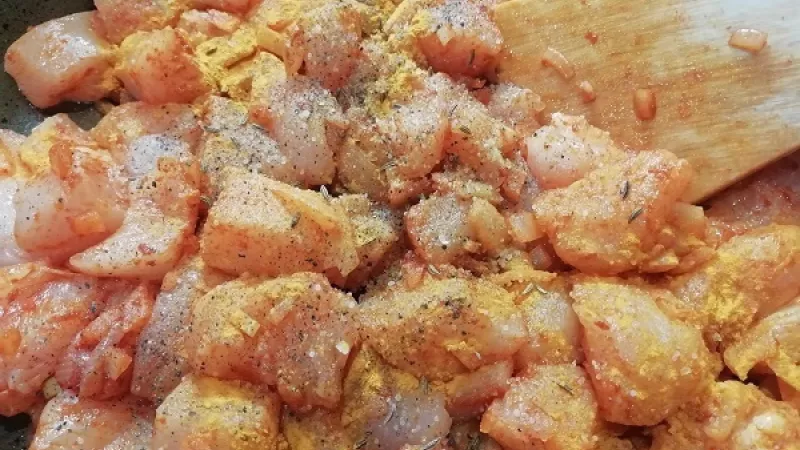 2. Cibuľu orestujeme do sklovita, zasypeme mletou červenou paprikou. Ihneď pridáme morčacie kocky a korenie podľa chuti -  soľ, mleté čierne korenie, rascu, kurkumu a roztlačený cesnak.