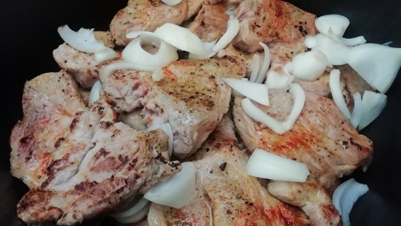 3. Cibuľu a cesnak očistíme, nakrájame na plátky. Do zapekacej misy striedavo vrstvíme opečenú bravčovú krkovičku, cibuľu a cesnak. Pridáme aj výpek (šťavu) z mäsa.