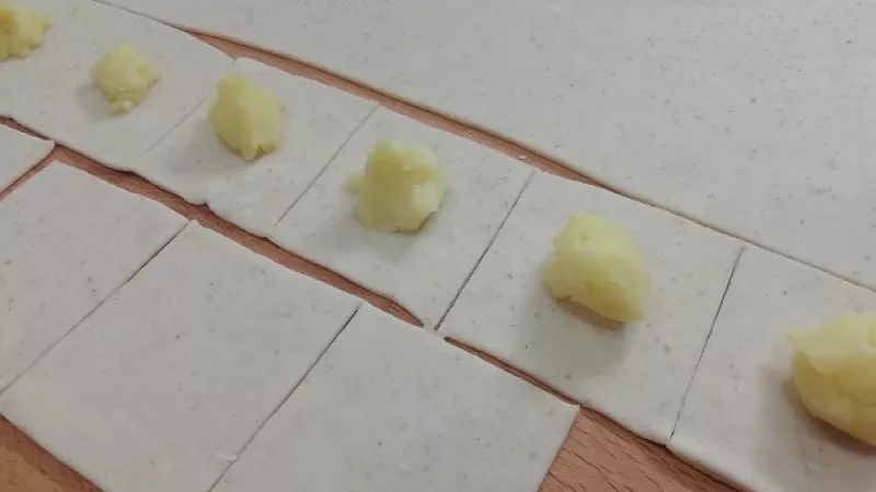 2. Cesto si na pomúčenej doske vyvaľkáme natenko, hrúbky 3 mm. Nožom narežeme štvorce veľkosti cca 5x5 cm, môžeme aj väčšie. Záleží, aké veľké pirohy si chceme pripraviť. Na každý štvorček ukladáme do stredu plnku. Lekvár by mal byť hustý, aby nevytiekol.