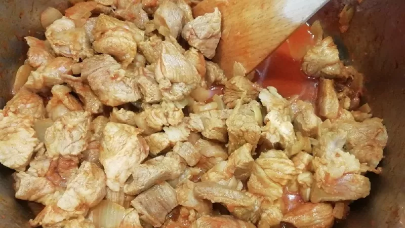 2. Cibuľu očistíme a nakrájame nadrobno. Na bravčovej masti (oleji) si ju orestujeme do sklovita, zasypeme mletou červenou paprikou, premiešame. Pridáme aj nakrájané mäso.