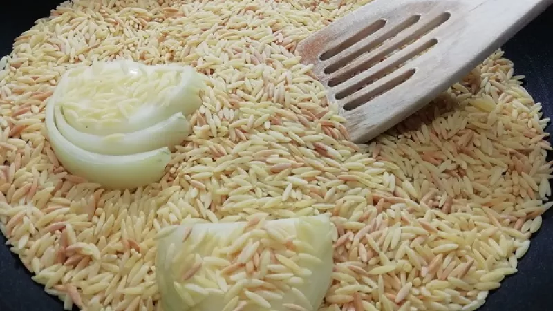 2. Na kvalitnej panvici si nasucho opražíme slovenskú ryžu spolu s očistenou rozpolenou cibuľou.