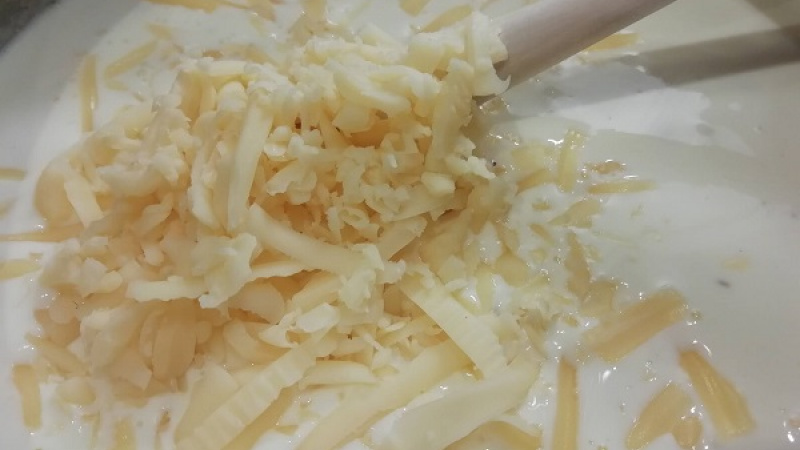 2. Do omáčky pridáme aj obľúbený syr, ktorý nastrúhame najemno. Prevaríme. Omáčku môžeme ešte zriediť mliekom, ak je hustejšia, dochutíme soľou a čiernym korením.