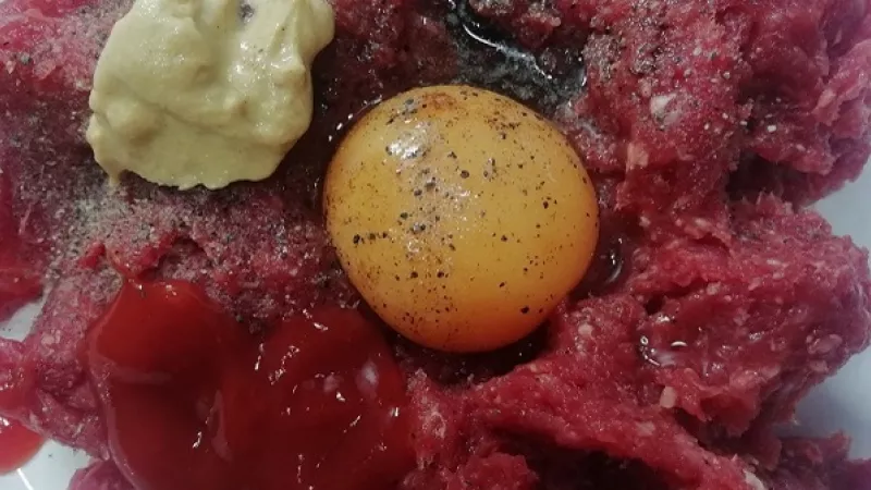 2. Mäso si môžeme zakúpiť už hotové, ktoré je dostupné v obchodoch. Do misy vložíme mäso, pridáme žĺtky, nadrobno nakrájanú cibuľu.