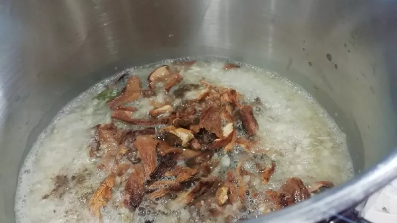 5. K juške pridáme od vody vytlačené huby, rozpolený cesnak, celé čierne korenie. Jušku s hubami povaríme 15 minút. Sledujeme aj mäso, ak je potrebné, môžeme ho podliať. Veľa šťavy však nepotrebujeme.