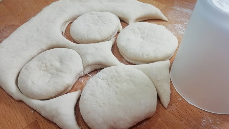 4. Ak zdvojnásobí objem, preložíme ho na drevenú dosku, ktorú sme si posypali múkou, aby sa cesto nelepilo. Cesto vyvaľkáme na hrúbku 1,5 cm, pomúčeným pohárikom vykrojíme kolieska. 