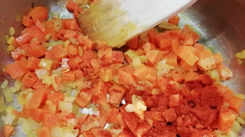 3. Keď je cibuľa sklovitá, pridáme na malé kocky nakrájanú mrkvu. Restujeme približne 5 minút, kvôli chuti a farbe polievky. Potom pridáme mletú červenú papriku. 