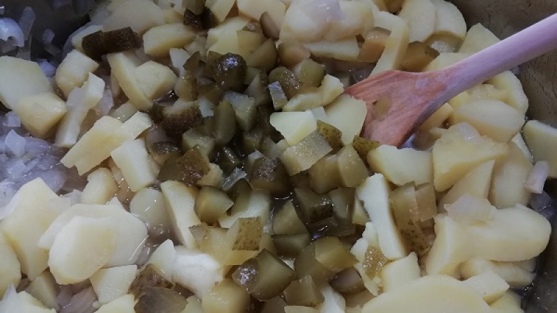 4. Kyslé uhorky nakrájame nadrobno. Do väčšej misky pridáme nakrájané zemiaky s uhorkami, olivový olej, prilejeme nálev. Zemiakový šalát dobre premiešame, dochutíme, ak treba.