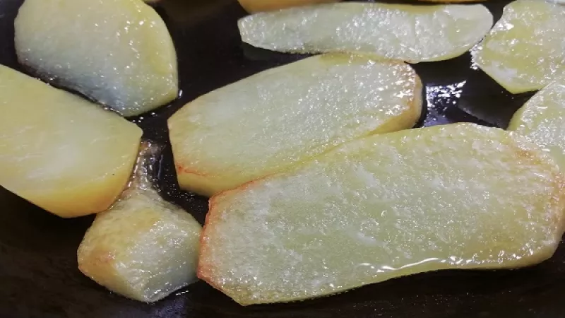 3. Kvalitnú panvicu rozohrejeme, pridáme repkový olej (bravčovú masť), cca 2 polievkové lyžice. Vložíme plátky zemiakov.