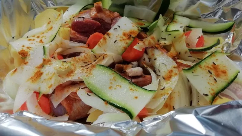 3. Cuketu nie je potrebné šúpať. Na mäso striedavo vrstvíme a koreníme zemiaky, mrkvu, petržlen, kaleráb, cuketu, cibuľu a cesnak. Pridáme aj maslo alebo olej.